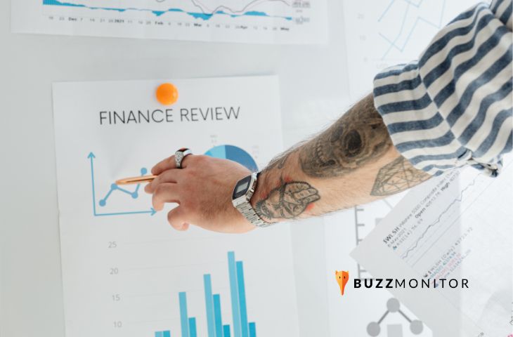 Braço tatuado aponta com caneta para gráfico de revisão financeira, ilustrando o cálculo de ROI em social media.