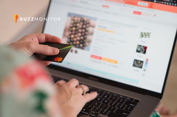 Mão segura cartão de crédito em frente ao notebook com página de compra online de varejo.