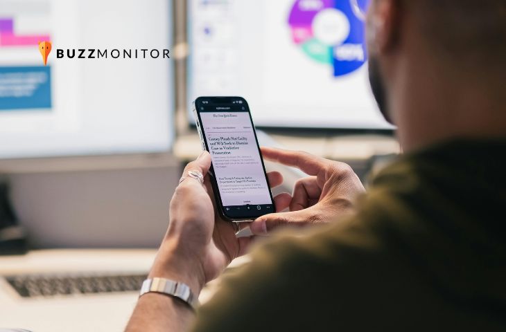 Homem lê manchetes de notícias no celular, com painel de dados ao fundo, representando monitoramento em tempo real.