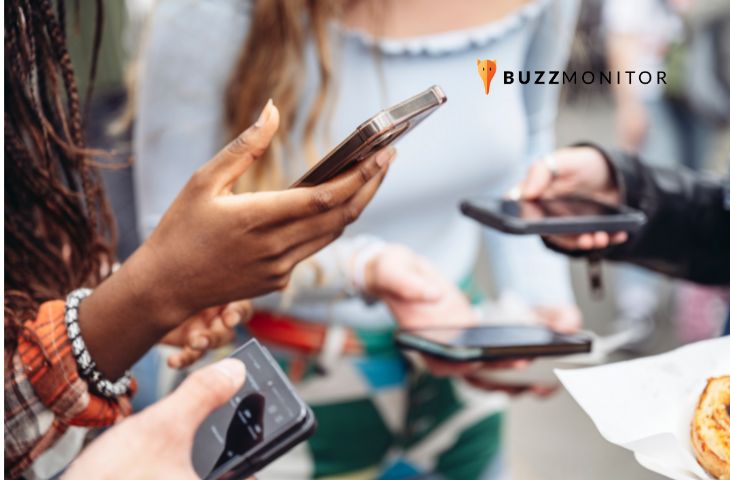 Grupo de pessoas usa smartphones simultaneamente ao ar livre, representando o comportamento do consumidor nas redes.
