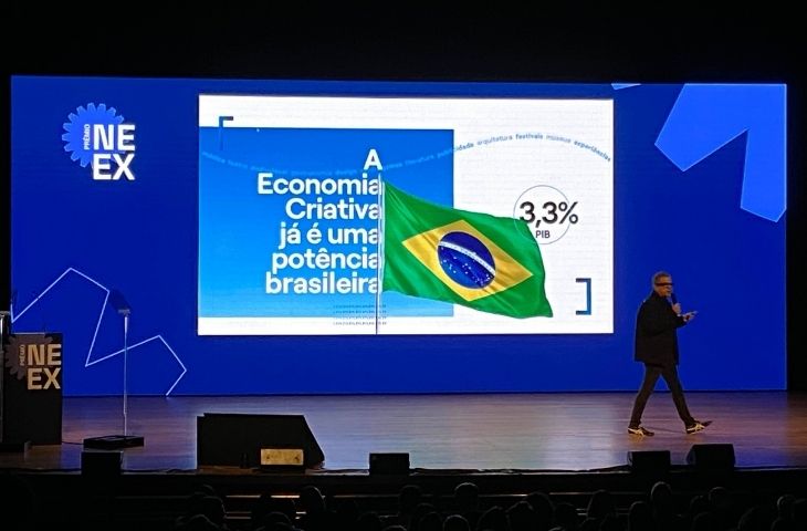 Palco do Prêmio NEEX 2026 com telão exibindo dados sobre a economia criativa brasileira