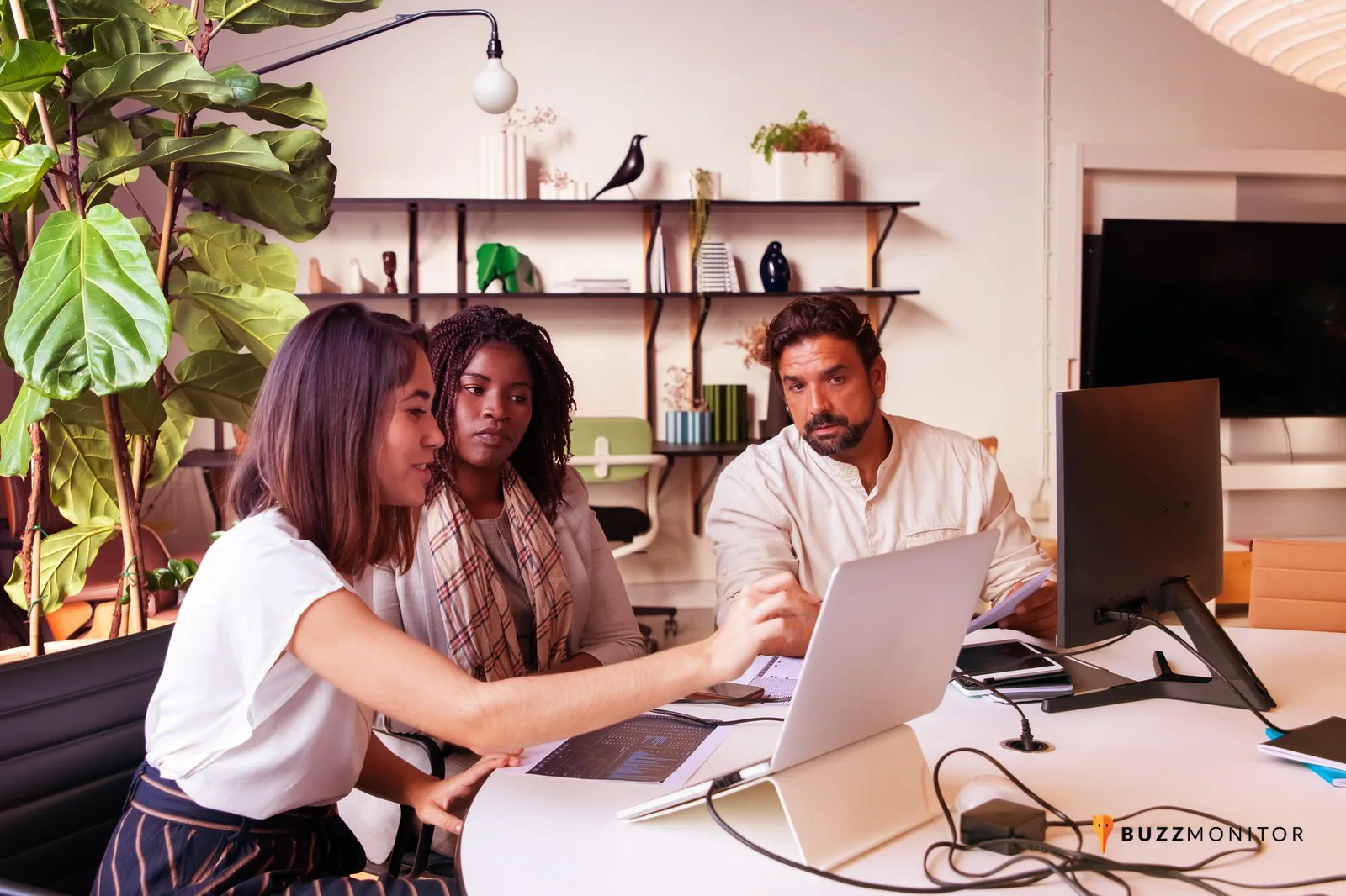 Equipo de colaboradores reunido alrededor de una computadora revisando contenidos para redes sociales