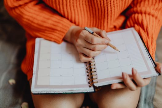 Woman writing on her daily planner Woman writing on her daily planner